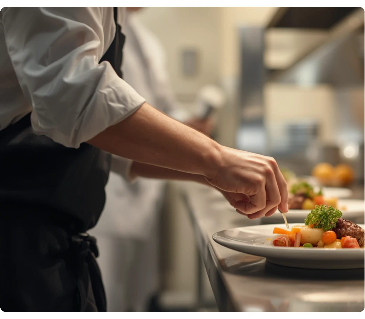 Chef plating a gourmet dish with warm coral accents in a professional kitchen